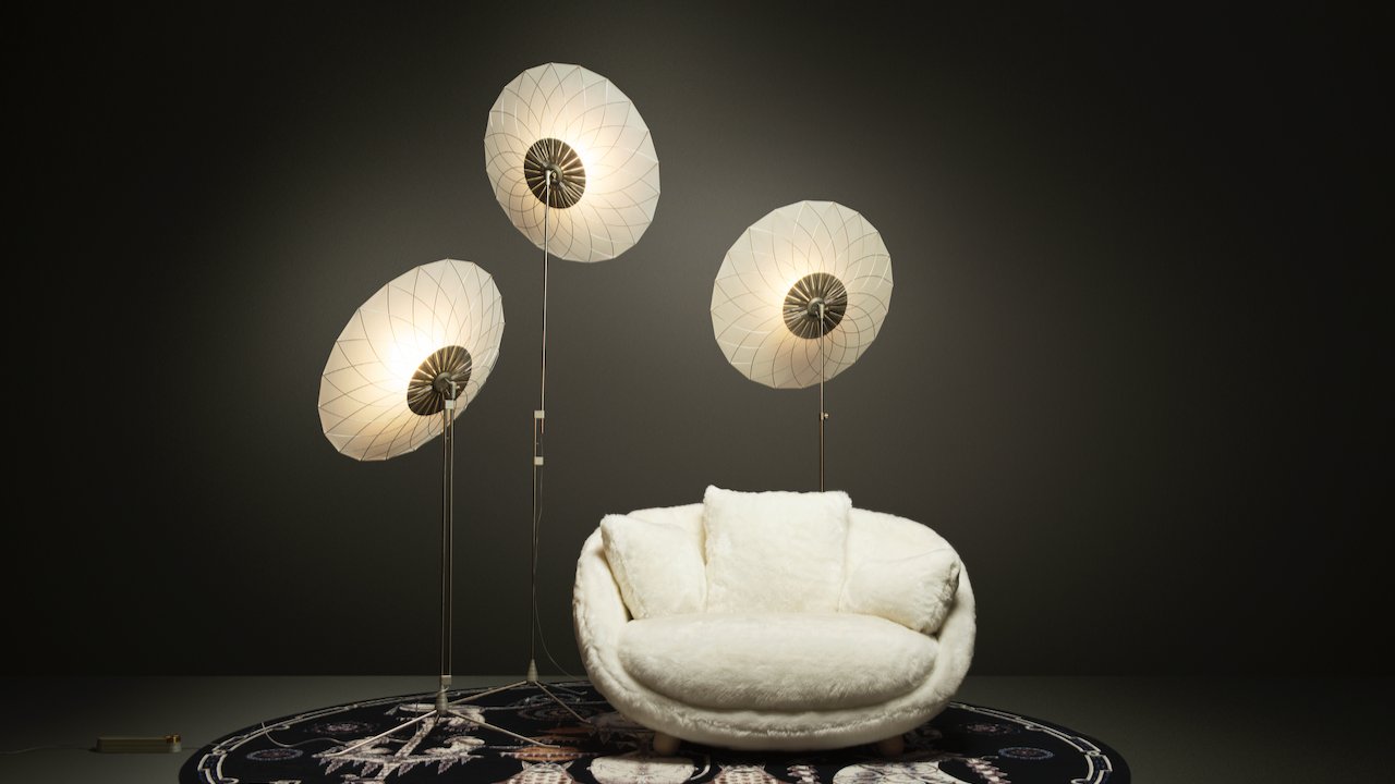 Pluizige witte fauteuil met drie schijfvormige lampen.