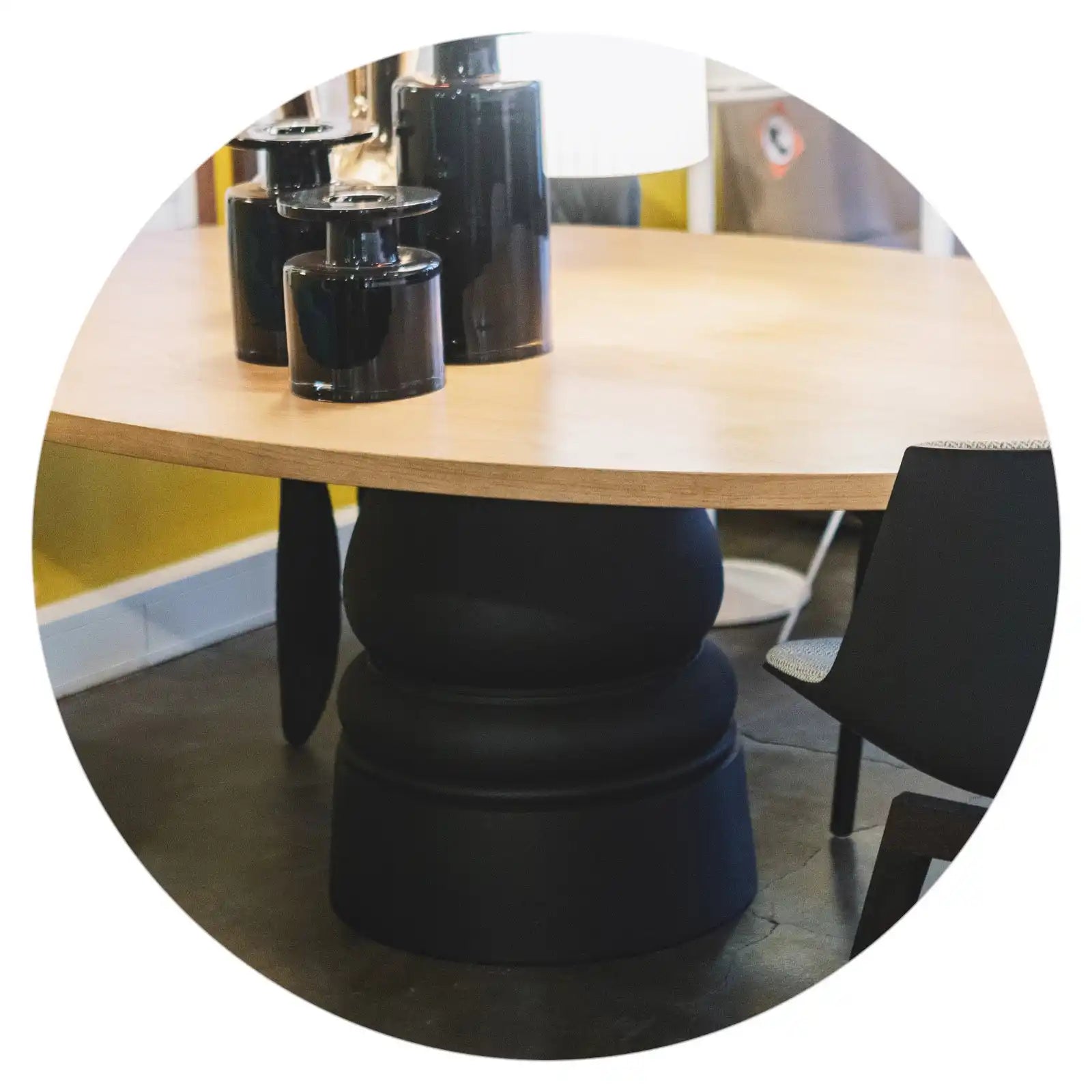 Ronde houten tafel met zwart voetstuk.